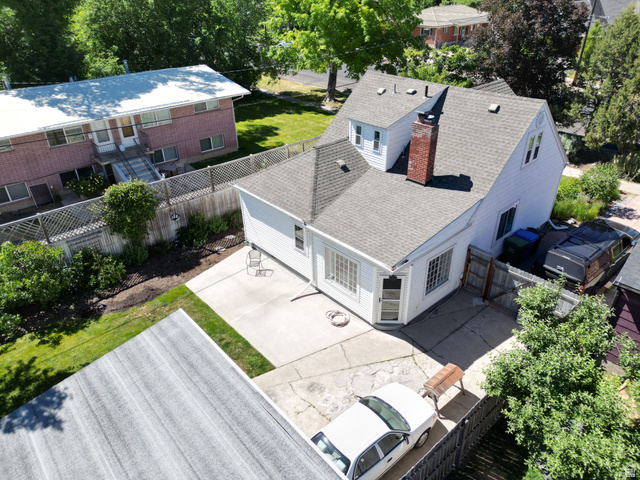 250 West 100 North Logan, UT 84321 - Photo 41 of 46 White siding residence featuring a gray shingle roof, a prominent brick chimney, and multiple dormer windows