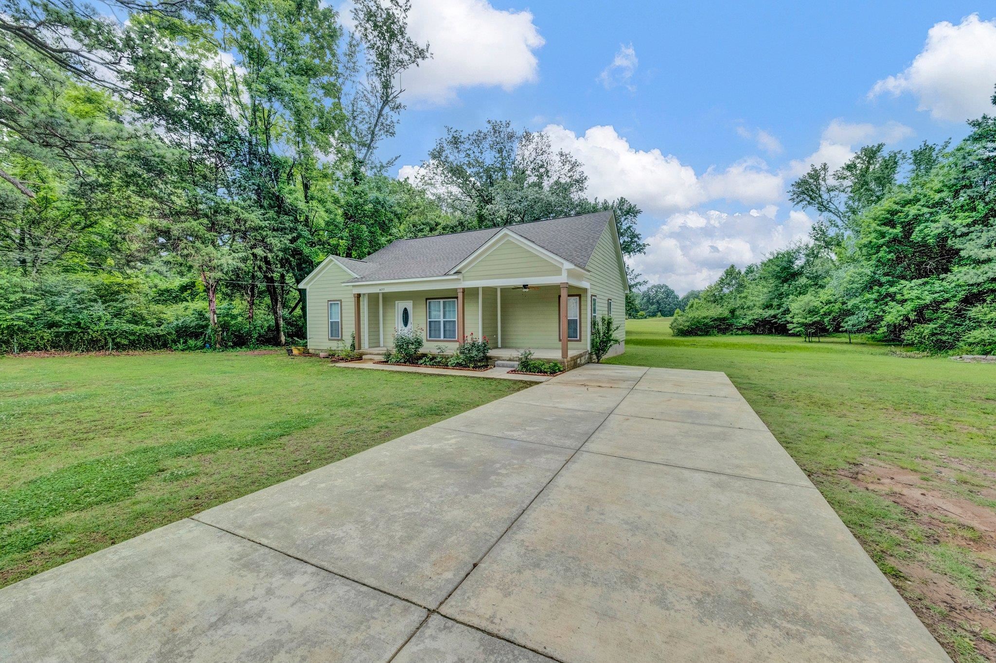 8077 Ellis Road Bartlett, TN 38133 - Photo 3 of 29 View of front facade featuring a front lawn, a porch, concrete driveway, and view of wooded area