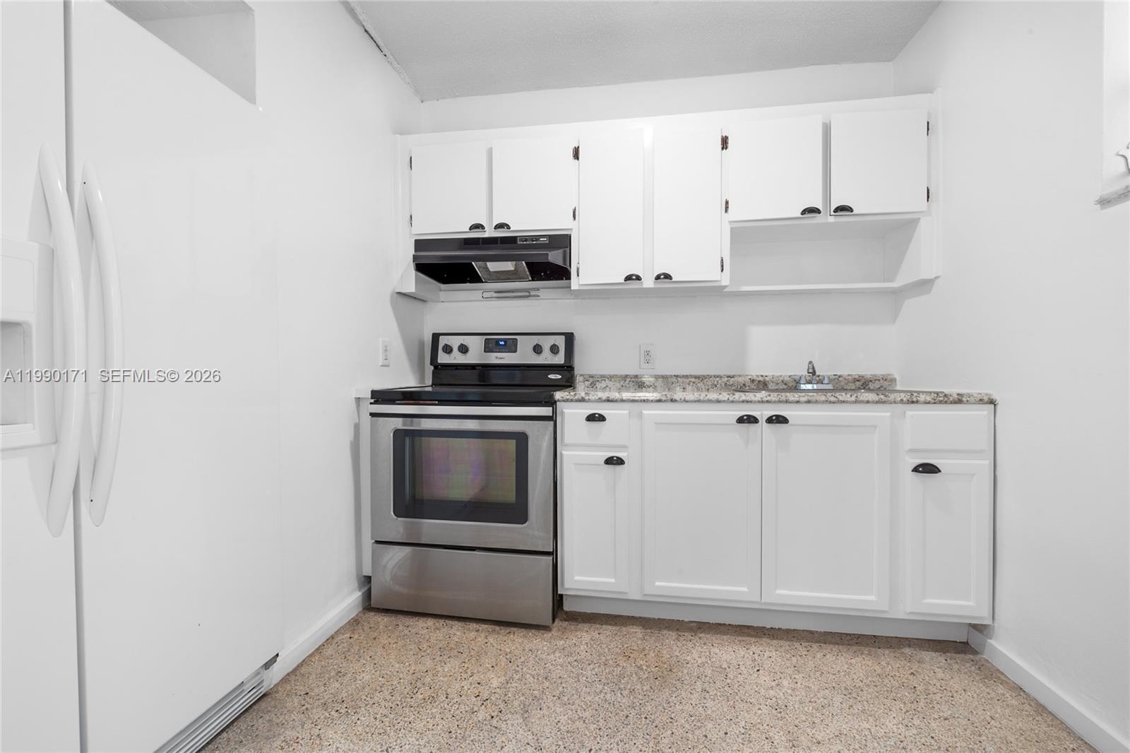 a kitchen with stainless steel appliances granite countertop white cabinets and stove top oven