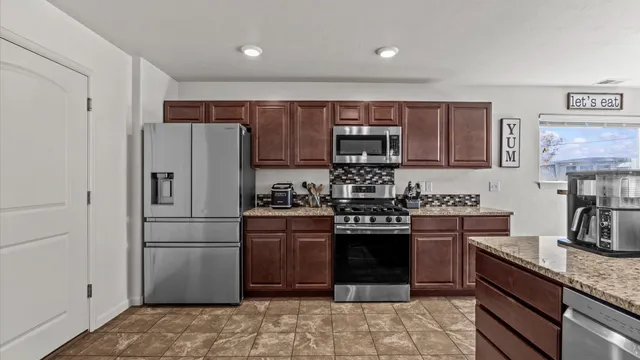 a kitchen with stainless steel appliances granite countertop a refrigerator stove a sink and dishwasher