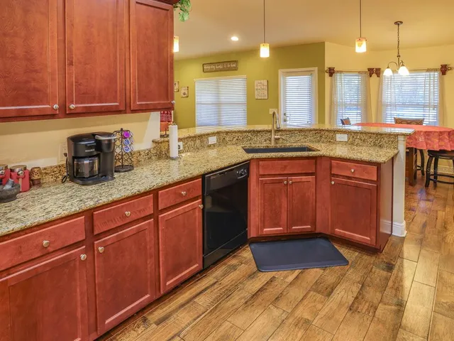 a kitchen with granite countertop wooden cabinets a sink and dishwasher