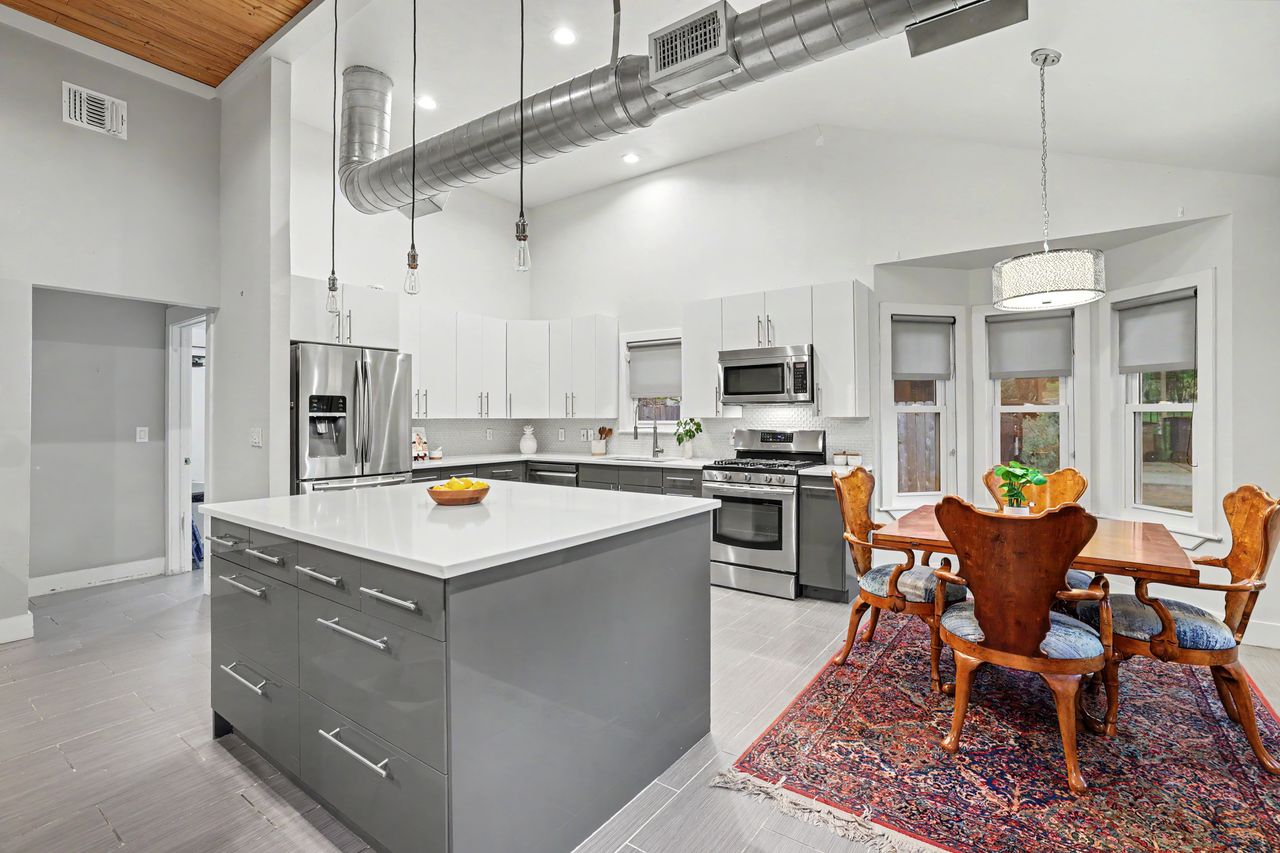 6903 Ardath Street Austin, TX 78757 - Photo 13 of 40 Kitchen featuring two tone color scheme, stainless steel appliances, a center island, a high ceiling, and modern cabinets