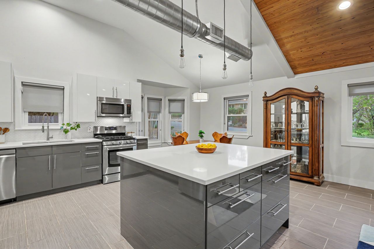 6903 Ardath Street Austin, TX 78757 - Photo 14 of 40 Two tone kitchen featuring two tone cabinets, stainless steel appliances, modern cabinets, hanging light fixtures, and tasteful backsplash
