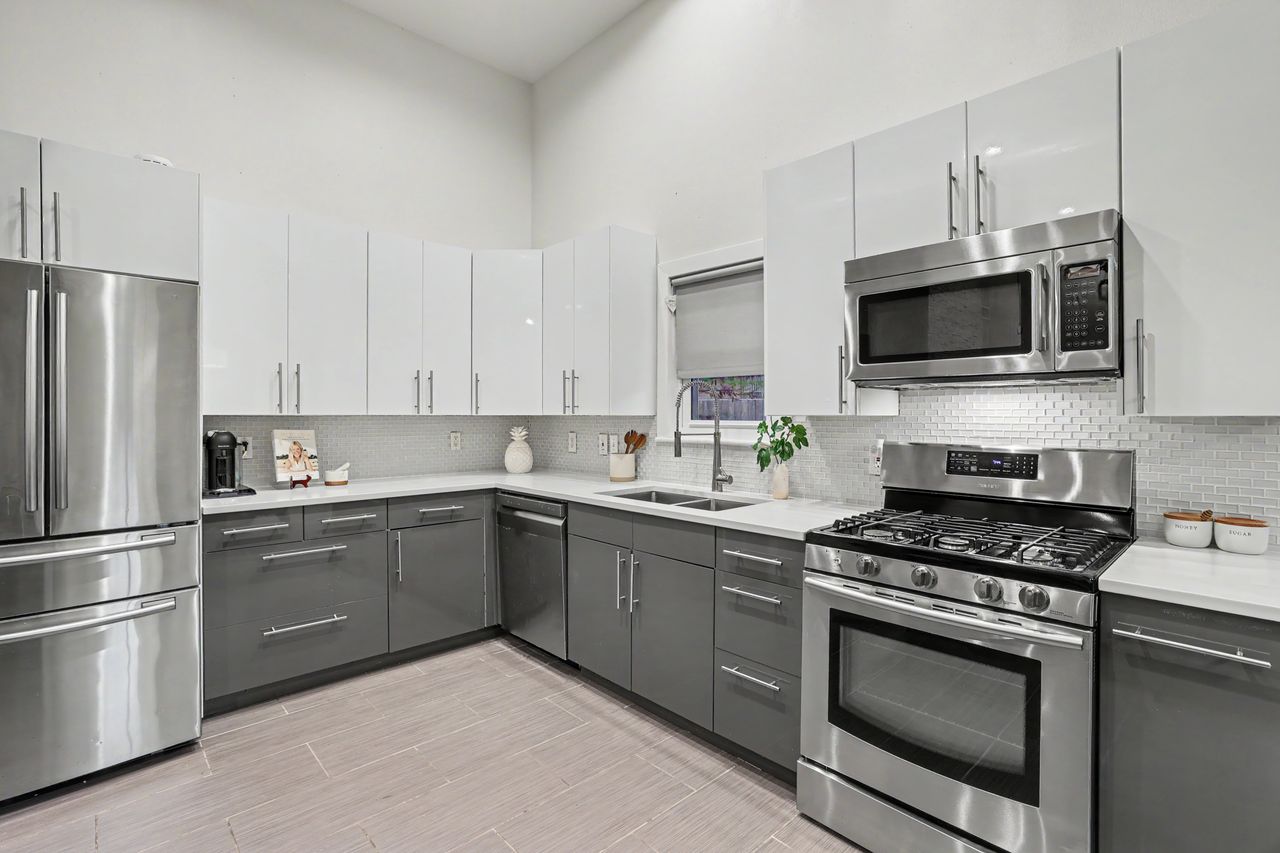 6903 Ardath Street Austin, TX 78757 - Photo 15 of 40 Kitchen with two tone cabinetry, stainless steel appliances, tasteful backsplash, modern cabinets, and wood tiled floors