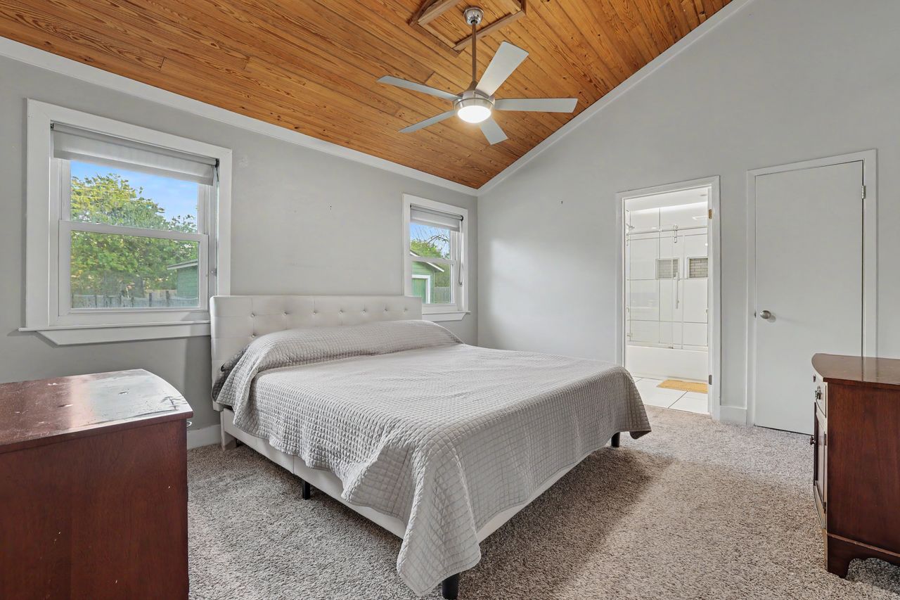6903 Ardath Street Austin, TX 78757 - Photo 20 of 40 Bedroom with light colored carpet, a ceiling fan, multiple windows, a vaulted wooden ceiling, and ensuite bathroom
