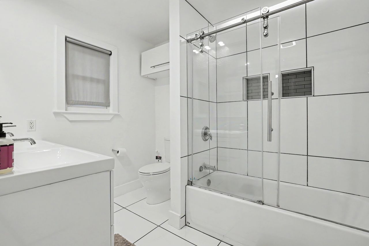 6903 Ardath Street Austin, TX 78757 - Photo 23 of 40 Full bath featuring vanity, light tile patterned floors, and shower / bath combination with glass door
