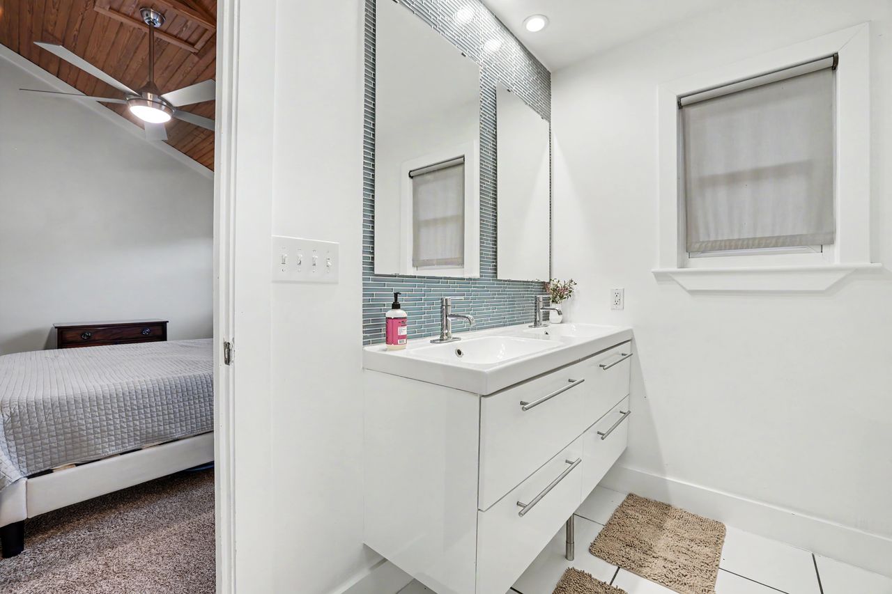 6903 Ardath Street Austin, TX 78757 - Photo 24 of 40 Ensuite bathroom with double vanity, decorative backsplash, and light tile patterned floors