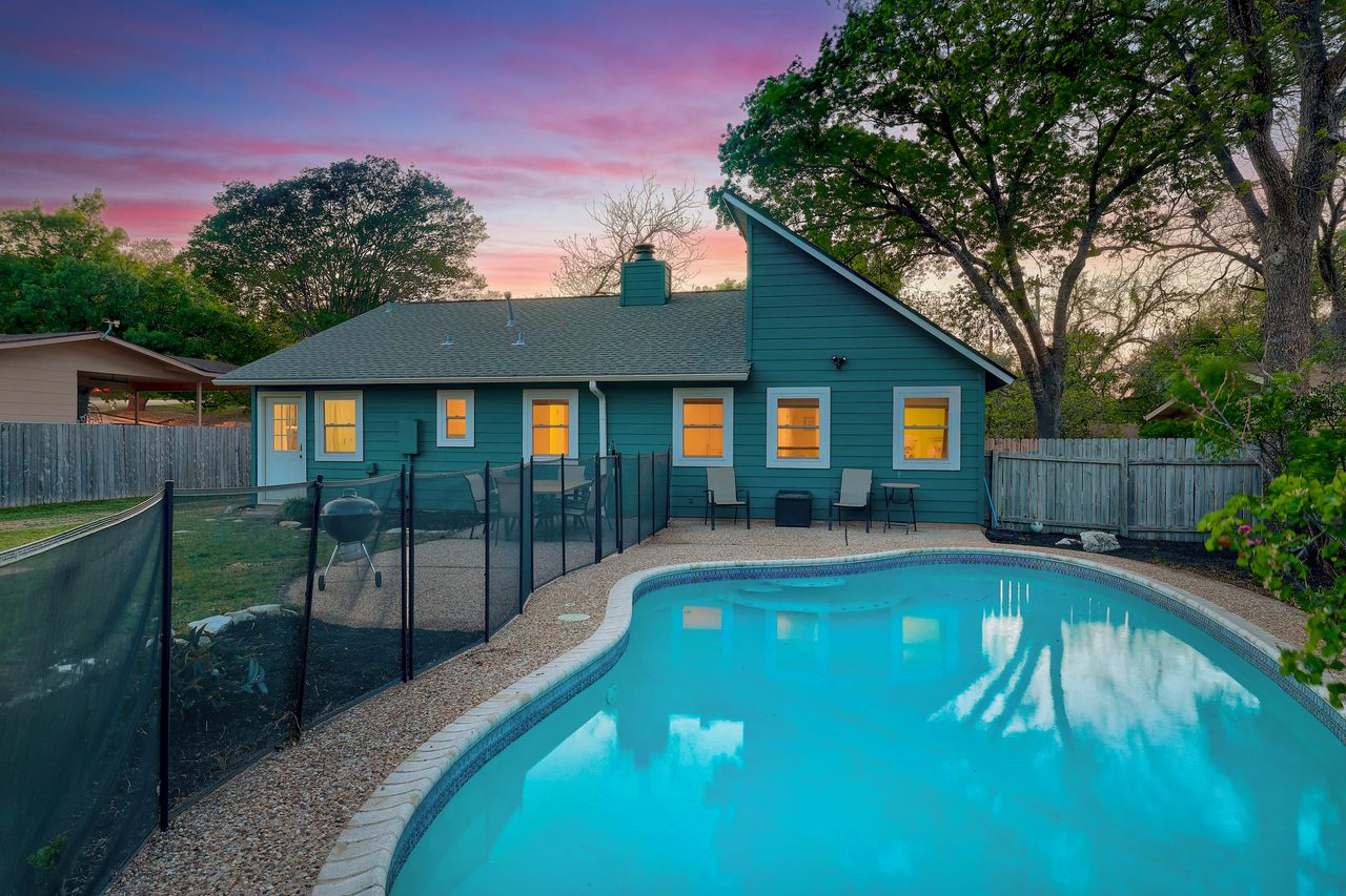 6903 Ardath Street Austin, TX 78757 - Photo 3 of 40 Back of house at dusk with a patio area, a chimney, and a fenced backyard