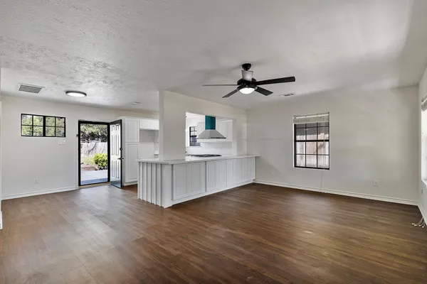 a view of an empty room with window and wooden floor