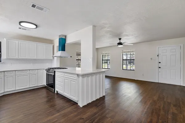 a kitchen with stainless steel appliances white cabinets and wooden floors