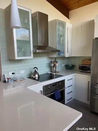 a kitchen with stainless steel appliances a sink a stove a refrigerator a counter space and cabinets