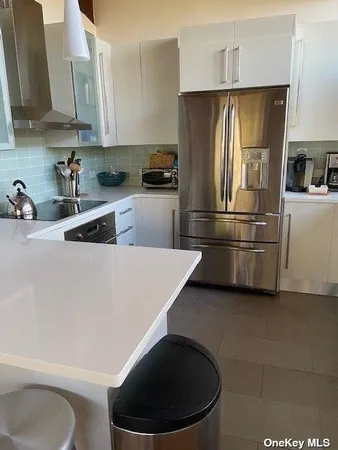 a kitchen with stainless steel appliances a refrigerator a sink a stove and white cabinets