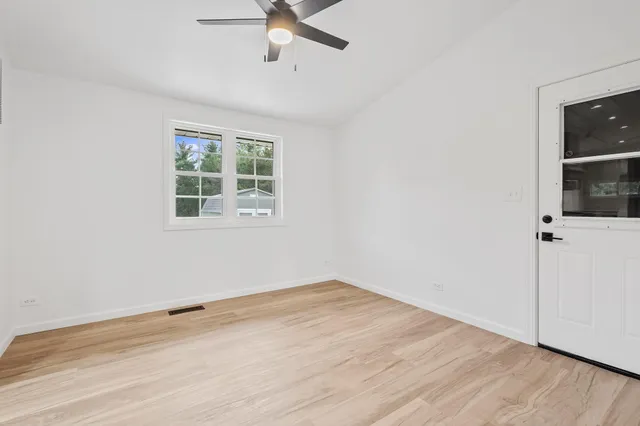 an empty room with a window and ceiling fan