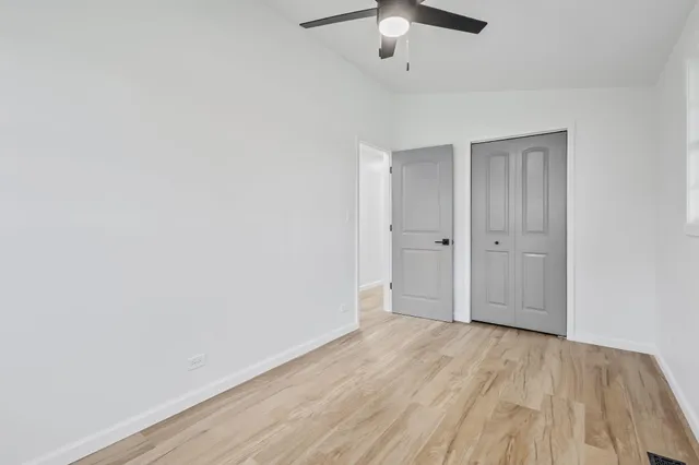 an empty room with a hardwood and ceiling fan
