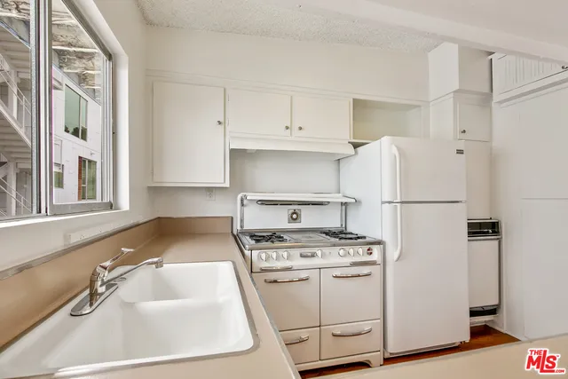 a kitchen with white cabinets sink and white appliances