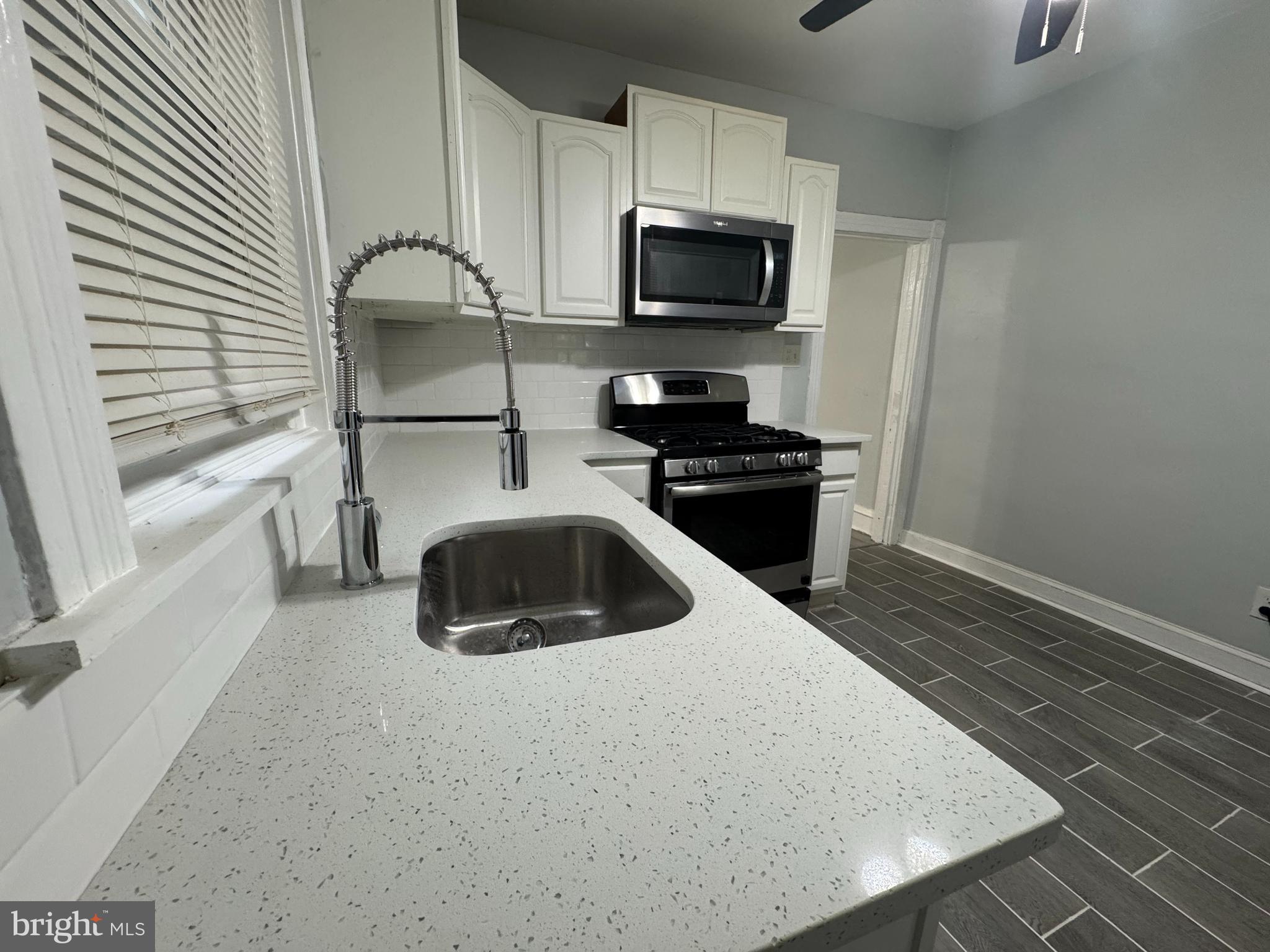 5502 Crowson Street Philadelphia, PA 19144 - Photo 6 of 16 a kitchen with a sink a microwave a refrigerator and cabinets