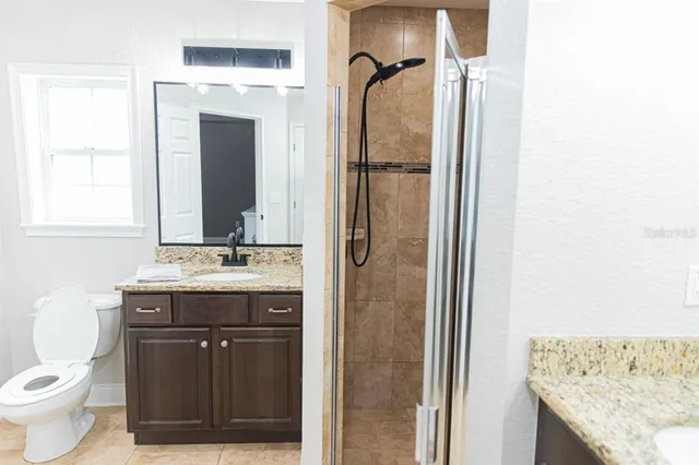 a bathroom with a granite countertop sink toilet and mirror