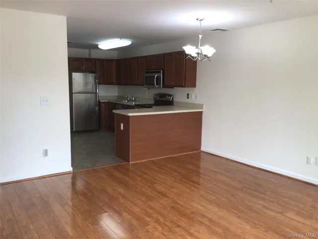 a kitchen with stainless steel appliances granite countertop a refrigerator a sink dishwasher a stove and a dining table with wooden floor