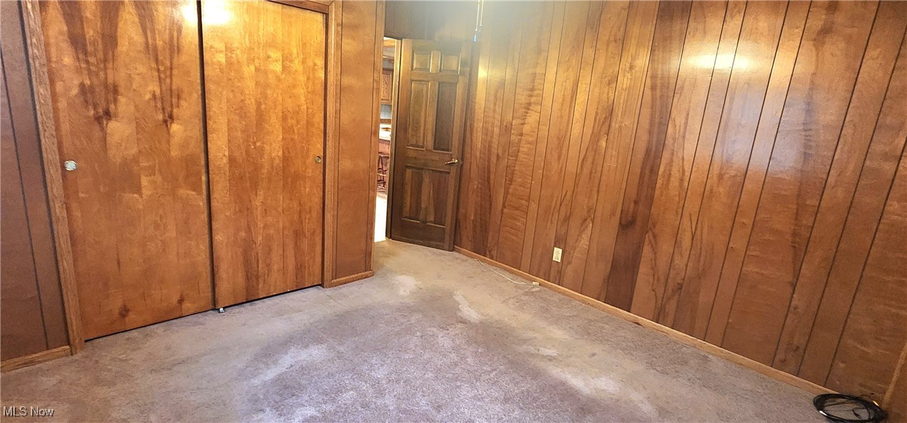 9090 Radcliffe Road Adamsville, OH 43802 - Photo 10 of 19 Unfurnished bedroom with light carpet, a closet, and wooden walls