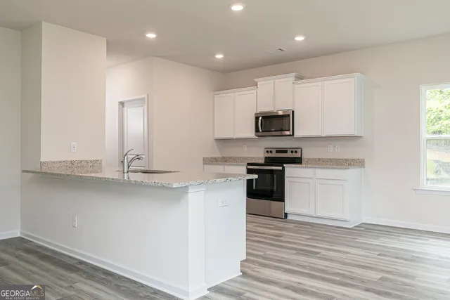a kitchen with granite countertop white cabinets and black stainless steel appliances