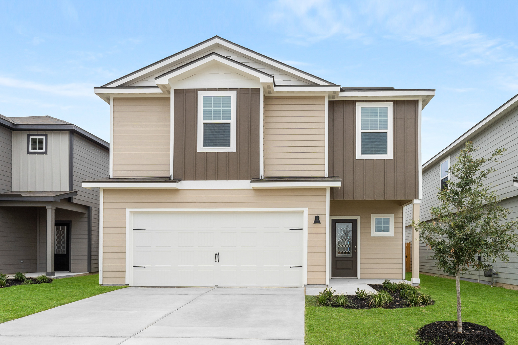 View of front of property with a garage, a front lawn, driveway, and board and batten siding