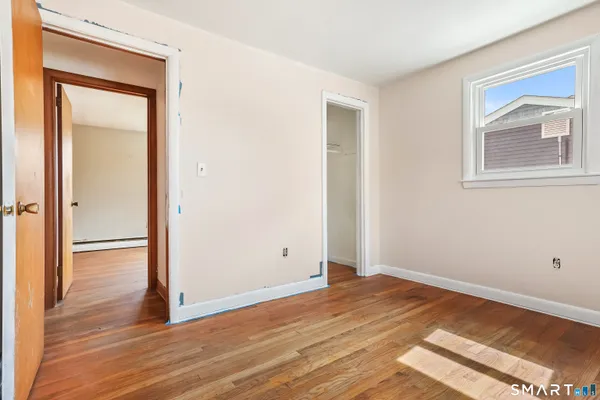 a view of empty room with wooden floor and fan
