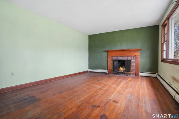 an empty room with wooden floor fireplace and windows