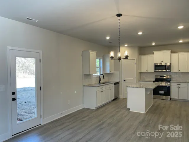 a kitchen with kitchen island granite countertop a sink cabinets and wooden floor