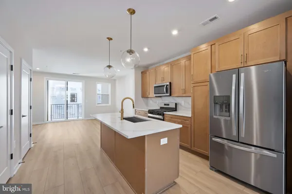 a kitchen with stainless steel appliances granite countertop a refrigerator a sink dishwasher a stove and white cabinets with wooden floor