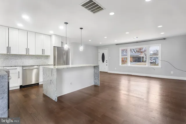 a view of kitchen with stove and white cabinets