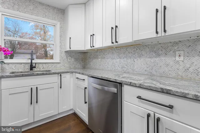 a kitchen with granite countertop white cabinets white appliances and a sink