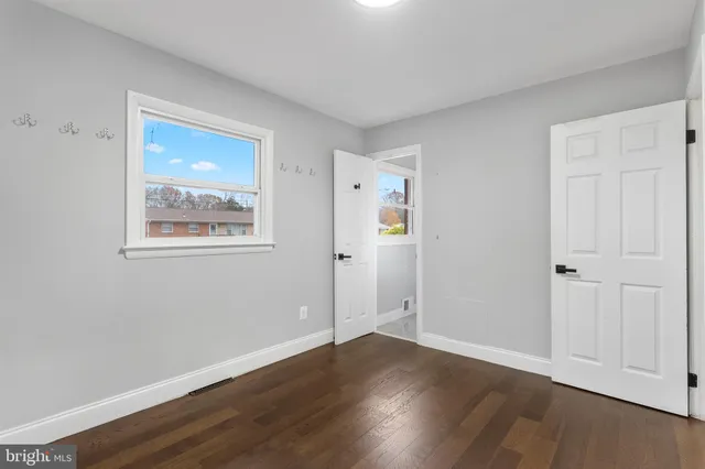 a view of an empty room with wooden floor and closet