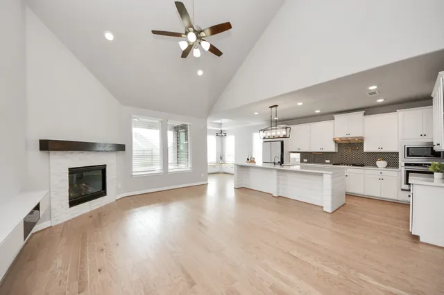 a large white kitchen with a sink and dishwasher a stove top oven with wooden floor