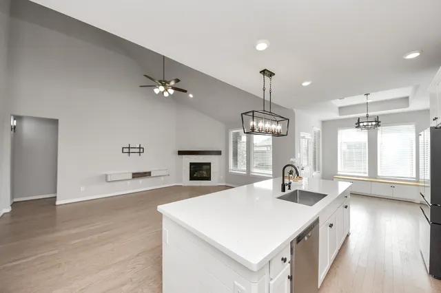 a large living room with stainless steel appliances furniture a chandelier open kitchen view