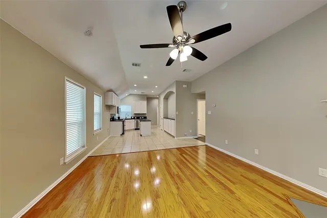 a view of empty room with wooden floor and fan