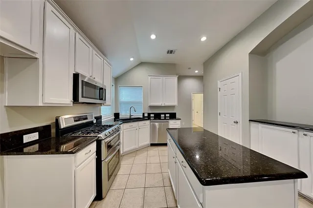 a kitchen with stainless steel appliances granite countertop a sink a stove and a refrigerator