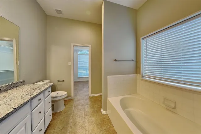 a bathroom with a granite countertop sink a large mirror and a bathtub