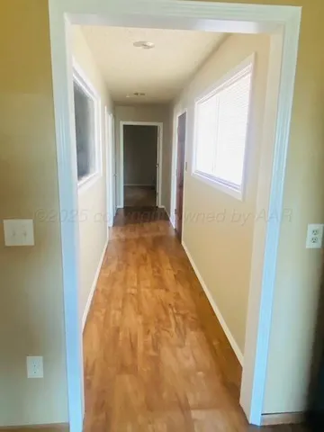 a view of a hallway with wooden floor and a bathroom