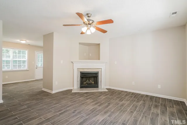 an empty room with windows fireplace and wooden floor