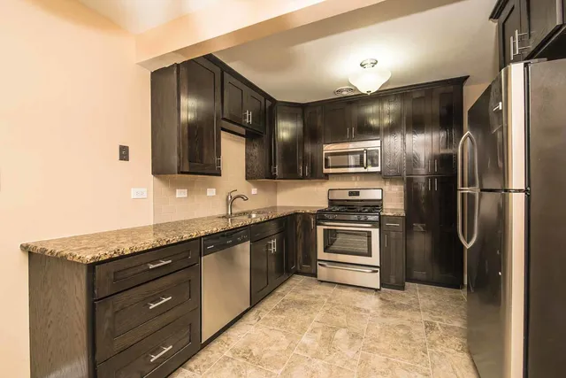 a kitchen with stainless steel appliances granite countertop a refrigerator and a stove
