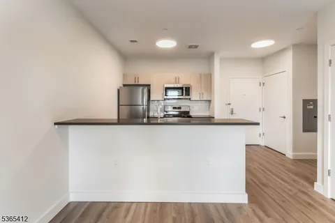 a kitchen with kitchen island a sink wooden floor and a refrigerator