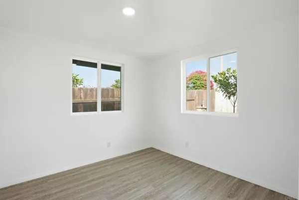 an empty room with wooden floor and windows
