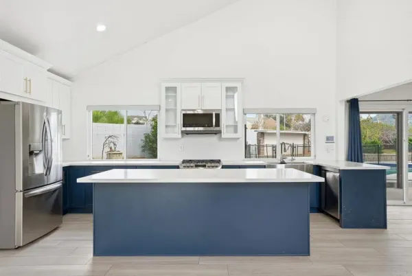 a large kitchen with kitchen island a large counter top stainless steel appliances and a window