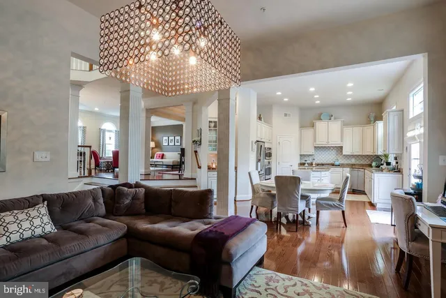 a living room with furniture kitchen view and a chandelier