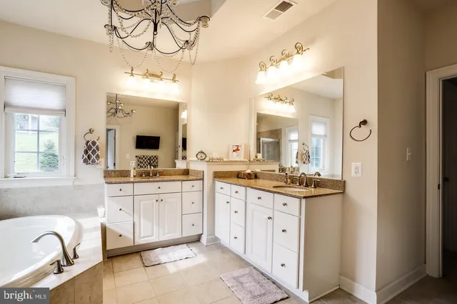 a spacious bathroom with a granite countertop sink a mirror and a bathtub
