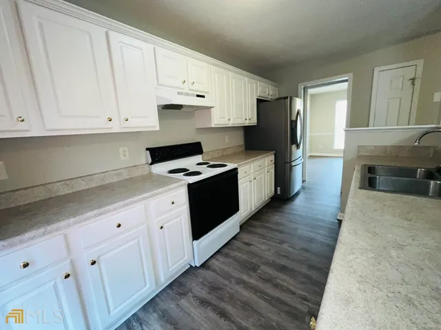 a kitchen with granite countertop a stove top oven a sink dishwasher and a refrigerator with wooden cabinets