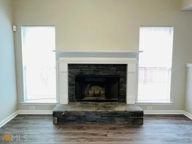 an empty room with wooden floor ceiling fan and windows