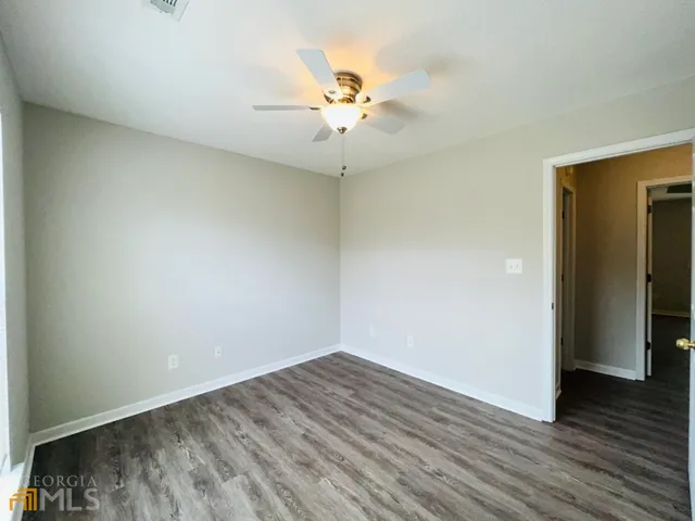 an empty room with wooden floor chandelier and windows