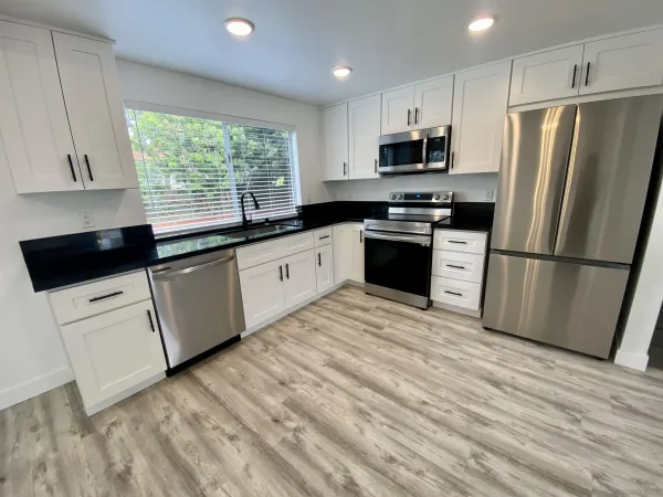 a kitchen with granite countertop a refrigerator stove top oven and sink