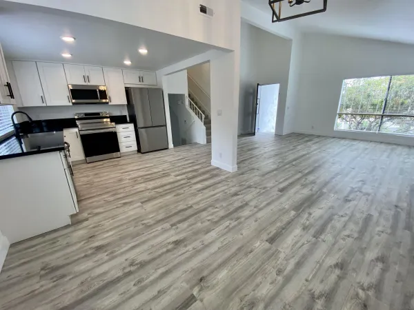 a kitchen with stainless steel appliances granite countertop a refrigerator a stove top oven a sink and dishwasher with wooden floor